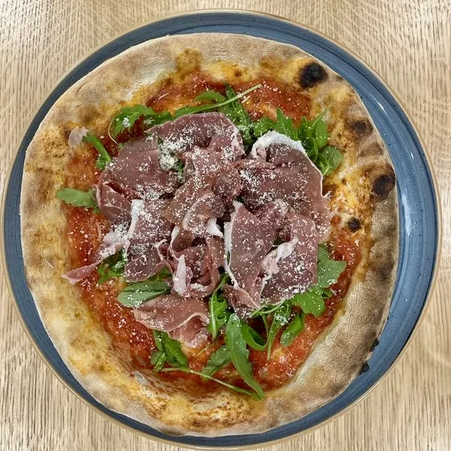 Pizza mit Parmaschinken und Rucola